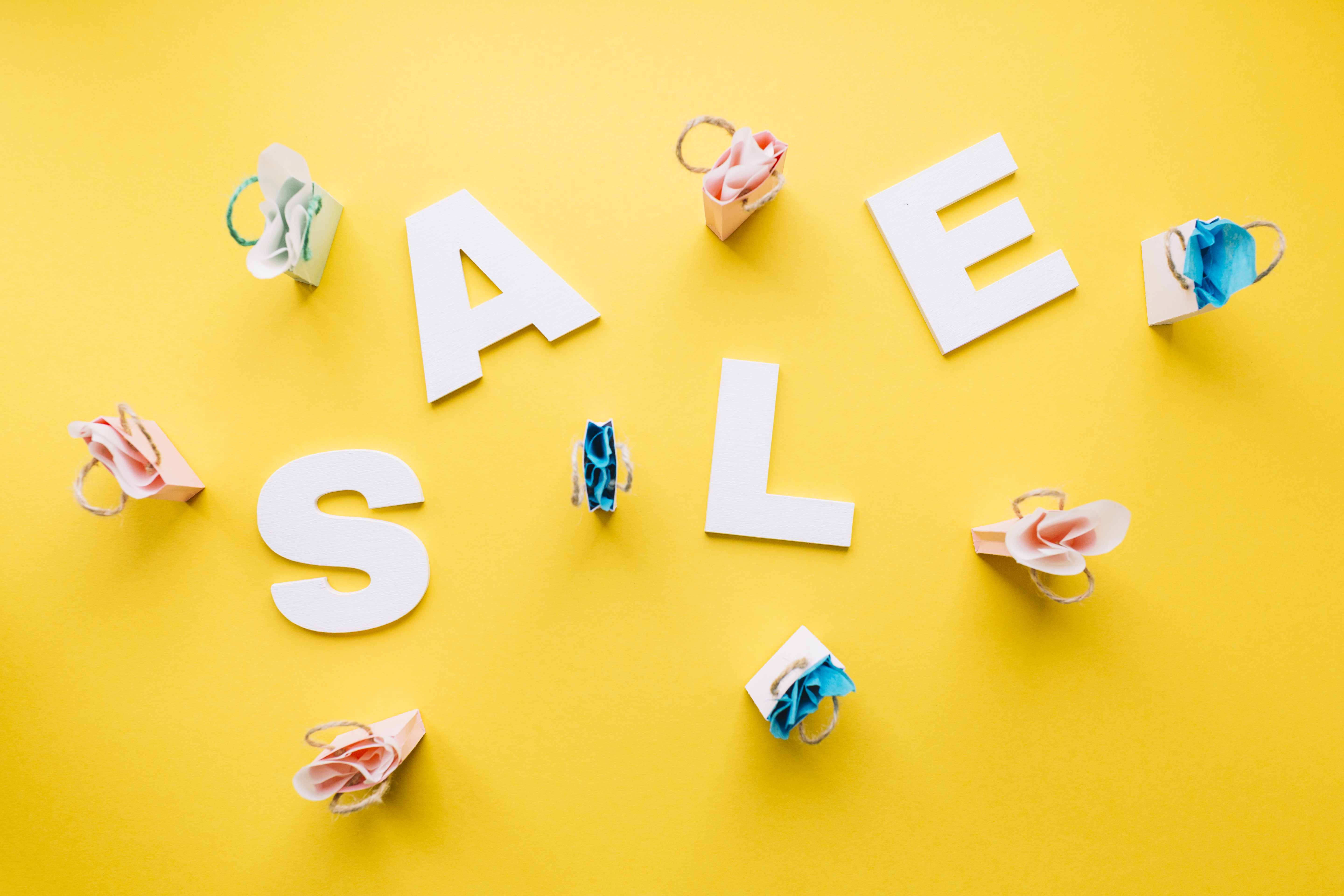 white-sale-alphabet-surrounded-with-miniature-shopping-bags-yellow-backdrop